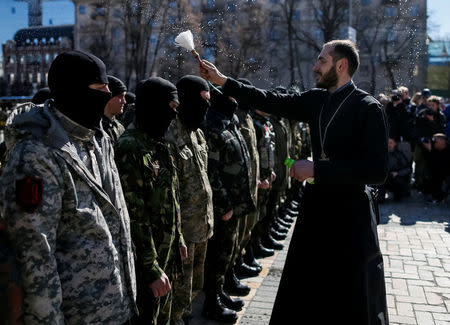 A priest sprinkles holy water on members of the Organization of Ukrainian Nationalists (OUN) before they depart to the frontline in eastern Ukraine, in central Kiev, Ukraine March 17, 2015. Picture taken March 17, 2015. REUTERS/Gleb Garanich