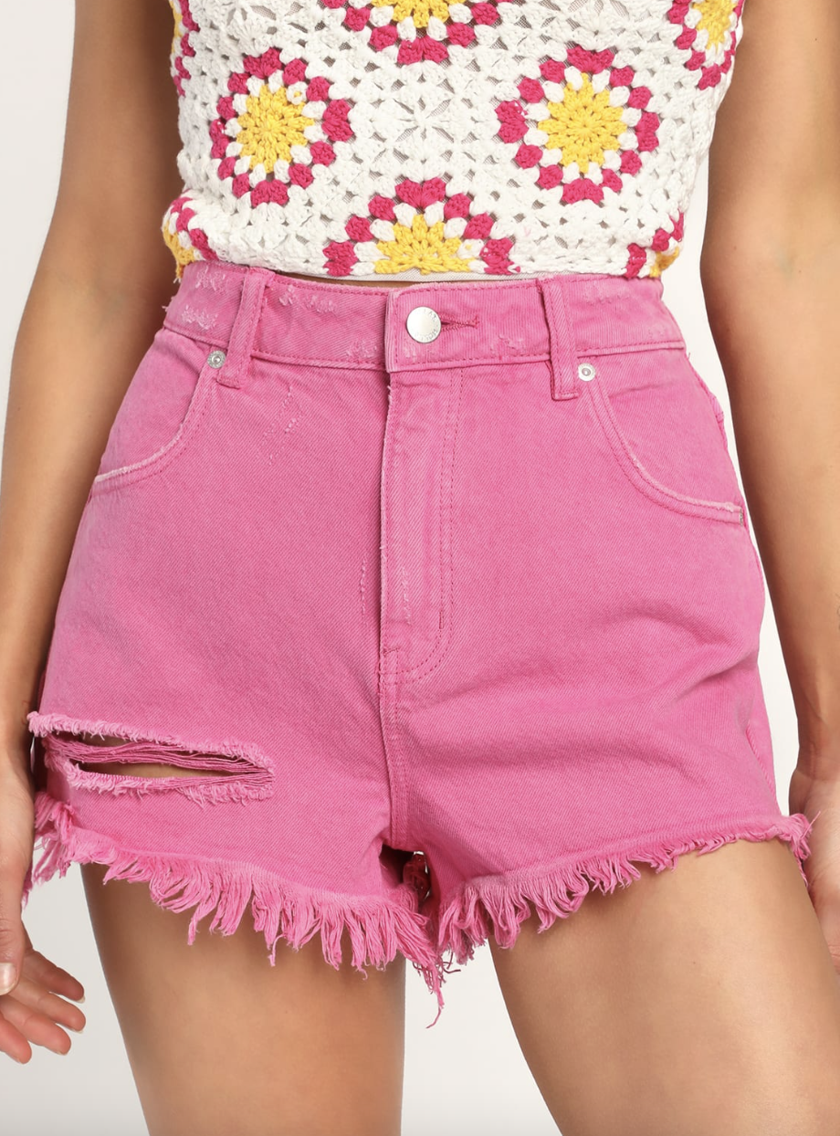 model in crochet top and pink Rolla's Dusters Magenta High Rise Distressed Denim Shorts (Photos via Lulus)