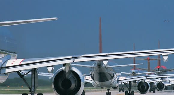 A view of the back of numerous airplanes in a row.