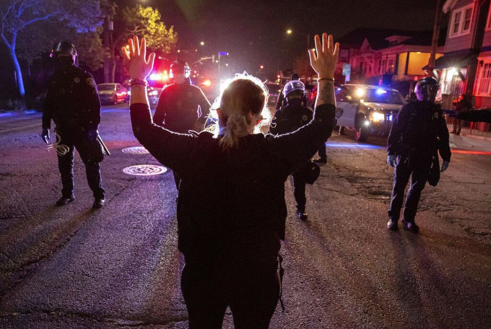 A demonstrator confronts a line of Oakland police officers during a protest against police brutality in Oakland, April 16, 2021. / Credit: Ethan Swope/AP