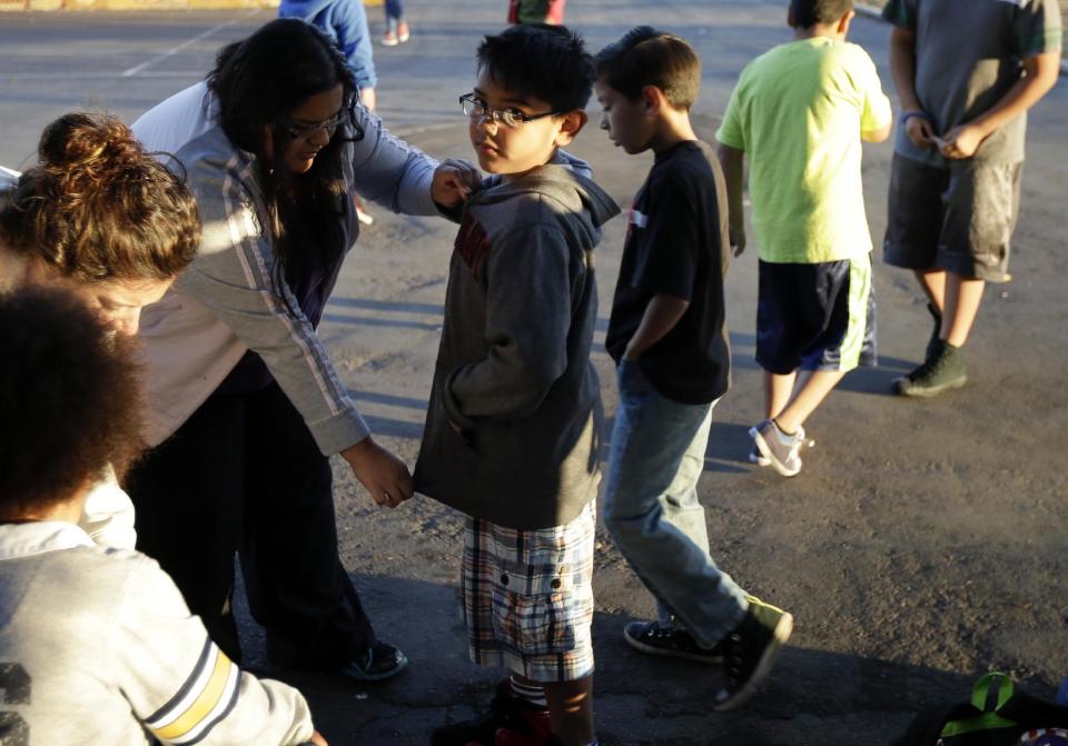 In this March 14, 2014 picture, Marina Beltran, left, zips up the jacket of her son Antonio before he takes part in an early morning running program at his elementary school in Chula Vista, Calif. Amid alarming national statistics showing an epidemic in childhood obesity, hundreds of thousands of students across the country are being weighed and measured. Beltran son’s Chula Vista Elementary School District is being touted as a model for its methods that have resulted in motivating the community to take action. (AP Photo/Gregory Bull)