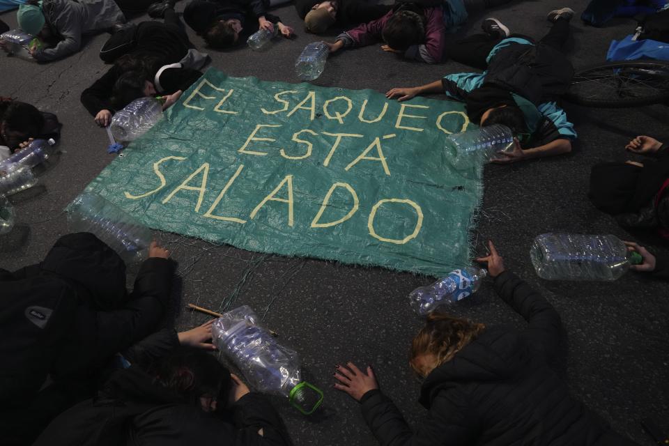 La gente se acuesta junto a un cartel durante una protesta en reclamo de soluciones urgentes a la crisis del agua en el centro de Montevideo, Uruguay, el miércoles 31 de mayo de 2023. (AP Foto/Matilde Campodonico)