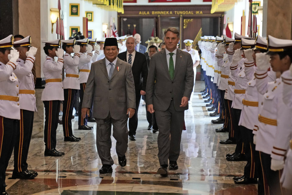 Honor guards salut as Australia's Deputy Prime Minister and Defense Minister Richard Marles, right, walks with Indonesian Defense Minister Prabowo Subianto after their meeting in Jakarta, Indonesia, Monday, June 5, 2023. (AP Photo/Dita Alangkara)