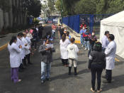 Juarez public hospital health workers wait on a street after a 7.5 earthquake sent them out from their work areas, in Mexico City, Tuesday, June 23, 2020. The earthquake centered near the resort of Huatulco in southern Mexico swayed buildings Tuesday in Mexico City and sent thousands into the streets. (AP Photo/Eduardo Verdugo)