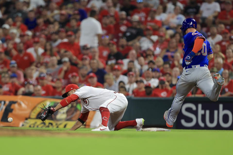 Cincinnati Reds' Joey Votto, left, attempts to field the ball as New York Mets' Pete Alonso, right, reaches first base safely on a fielders choice, during the seventh inning of a baseball game in Cincinnati, Tuesday, July 20, 2021. (AP Photo/Aaron Doster)