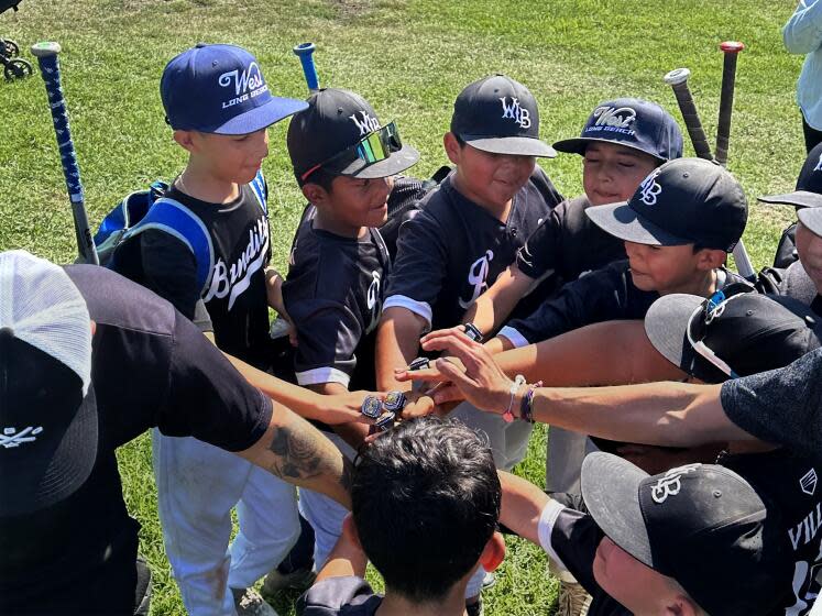 West Long Beach Little League players huddle after a game this summer. One of the league's equipment sheds was recently broken into, and a pitching machine and bases were stolen. <span class="copyright">(Courtesy of Louie Terrazas)</span>
