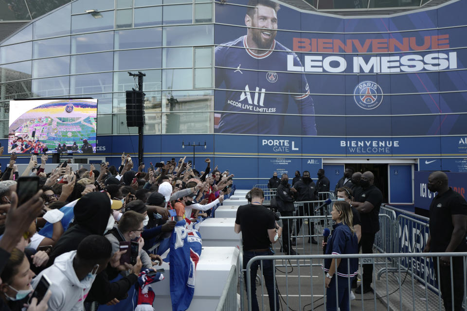 Paris Saint-Germain supporters gather outside the Parc des Princes stadium before Lionel Messi's press conference, Wednesday, Aug. 11, 2021 in Paris. Lionel Messi finally signed his eagerly anticipated Paris Saint-Germain contract on Tuesday night to complete the move that confirms the end of a career-long association with Barcelona and sends PSG into a new era. (AP Photo/Rafael Yaghobzadeh)