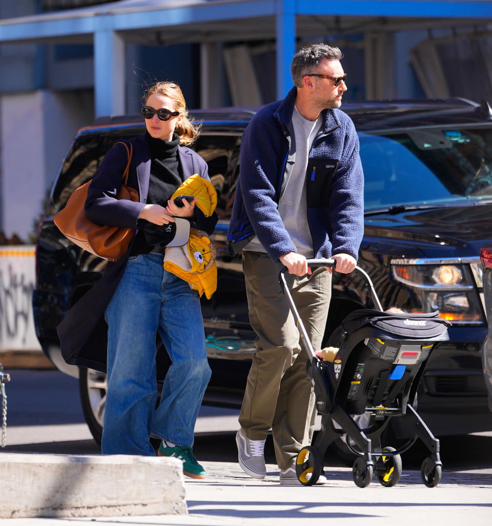 JLaw dressed casually and walking in the street with her husband, Cooke Maroney, who's pushing a stroller