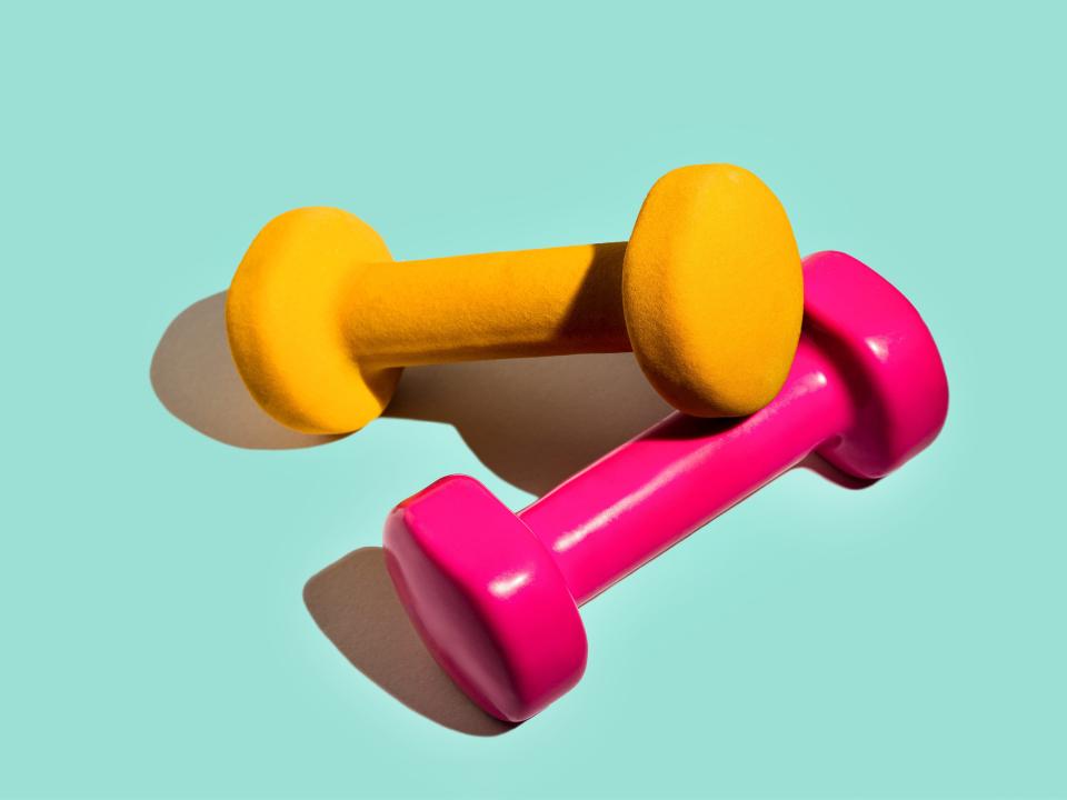 A stock image of a yellow and pink exercise weight on a blue background.