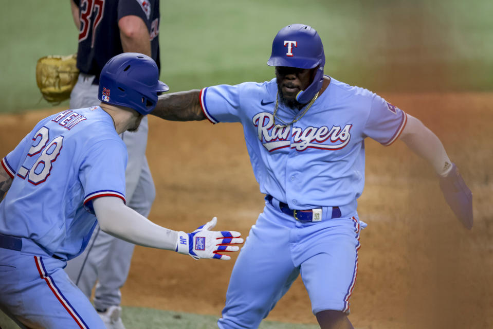 Texas Rangers' Adolis Garcia, right, celebrates with Jonah Heim after Garcia scored the go-ahead run in the the eighth inning of a baseball game against the Cleveland Guardians, Sunday, July 16, 2023, in Arlington, Texas. (AP Photo/Gareth Patterson)