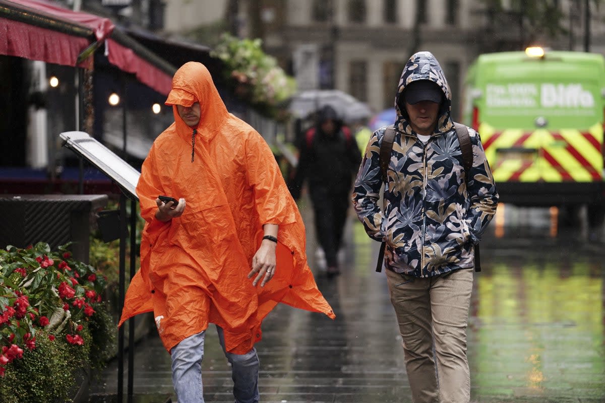 People caught during a heavy downpour of rain in Leicester Square, London (Jordan Pettitt/PA) (PA Wire)