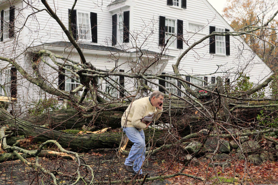 John Constantine makes his way out of his house after winds from Hurricane Sandy toppled a tree fell onto it in Andover, Mass. Monday, Oct. 29, 2012. Hurricane Sandy continued on its path Monday, as the storm forced the shutdown of mass transit, schools and financial markets, sending coastal residents fleeing, and threatening a dangerous mix of high winds and soaking rain. (AP Photo/Winslow Townson)