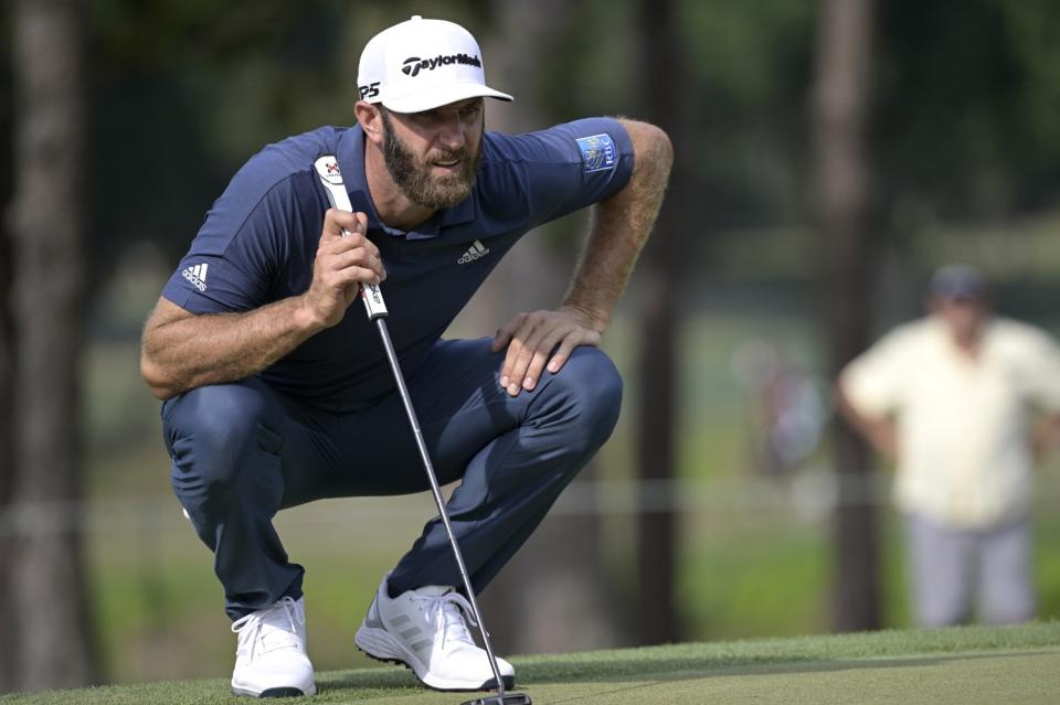 Dustin Johnson crouches while holding his club