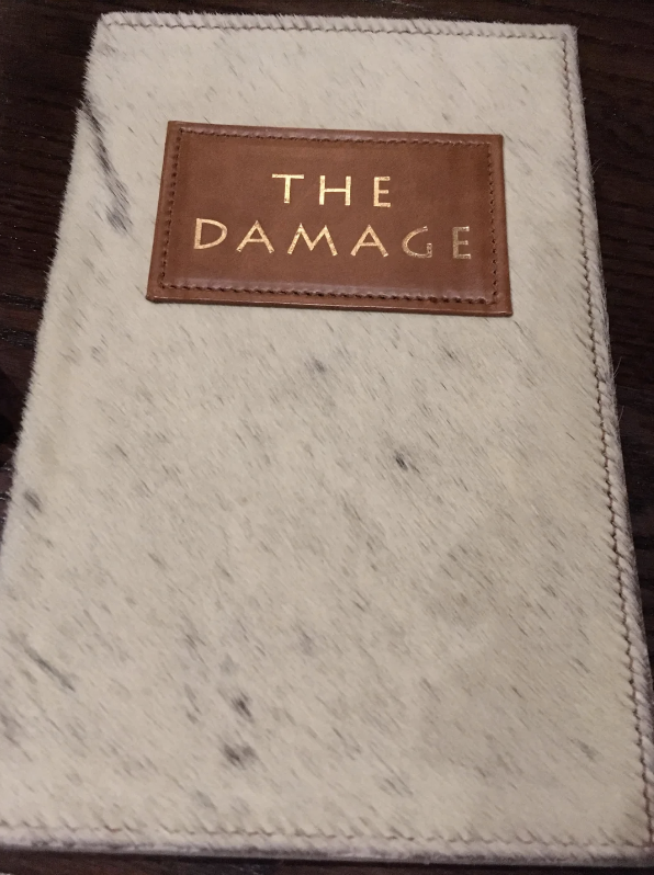 Menu cover with "THE DAMAGE" text, suggesting a humorous take on a bill presentation