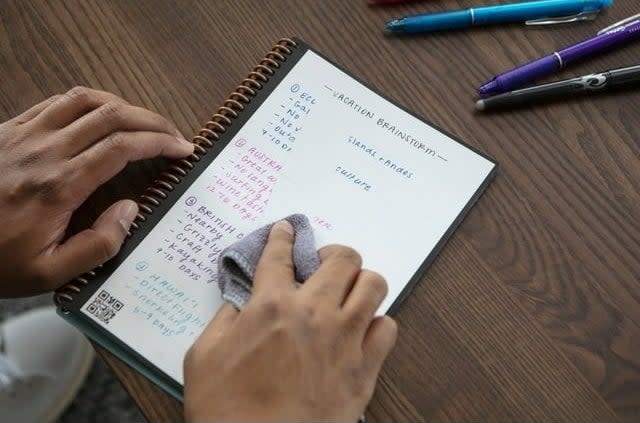 the notebook with writing on the pages and a model going to wipe it off with a cloth