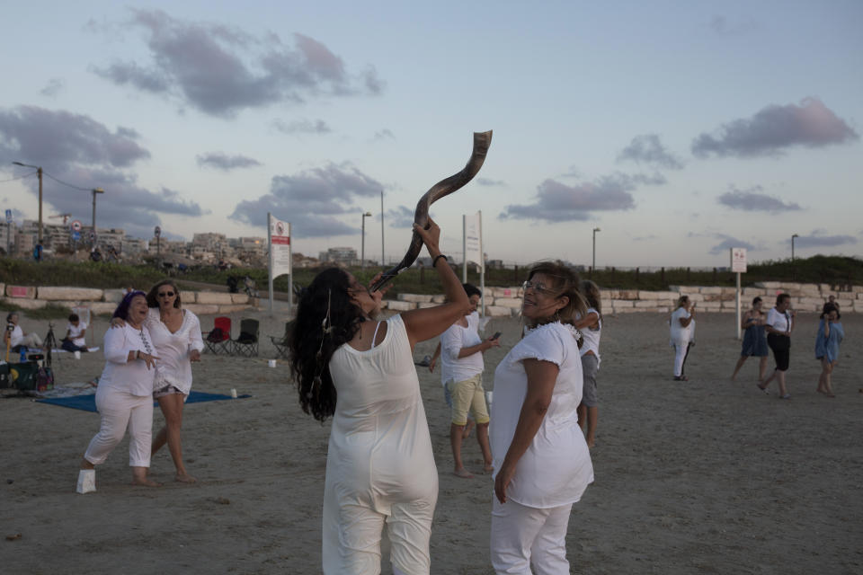 A woman holds a shofar before the start of a Tashlich ceremony, on the beach in Tel Aviv, Israel, Tuesday, Sept. 14, 2021. Tashlich, which means 'to cast away' in Hebrew, is the practice by which Jews go to a large flowing body of water and symbolically 'throw away' their sins by throwing a piece of bread, or similar food, into the water before the Jewish holiday of Yom Kippur, the holiest day in the Jewish year which starts at sundown Wednesday. (AP Photo/Maya Alleruzzo)