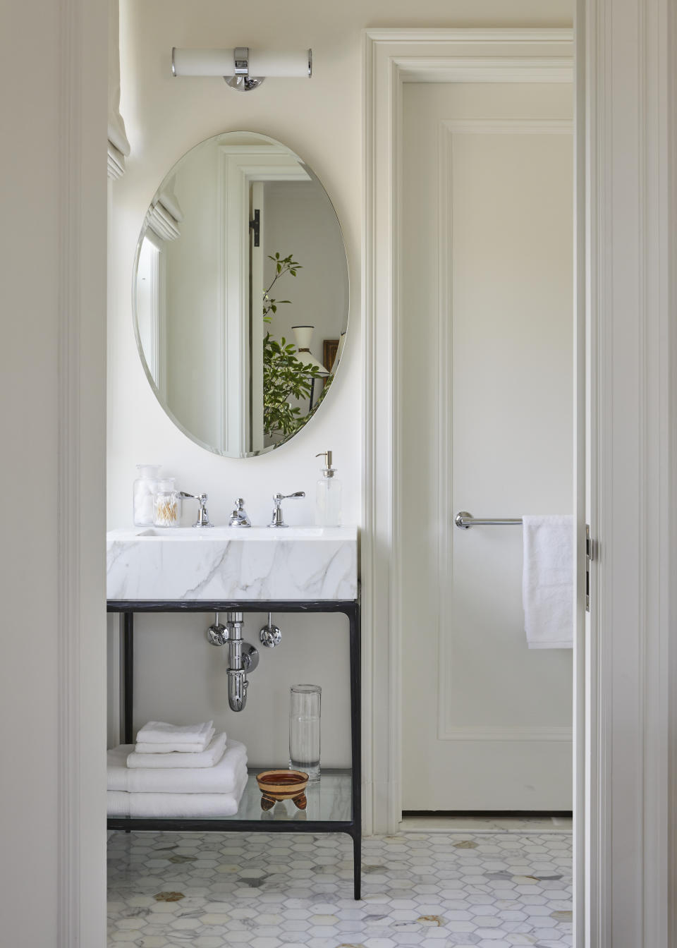 A whilte bathroom with a light bar above the mirror