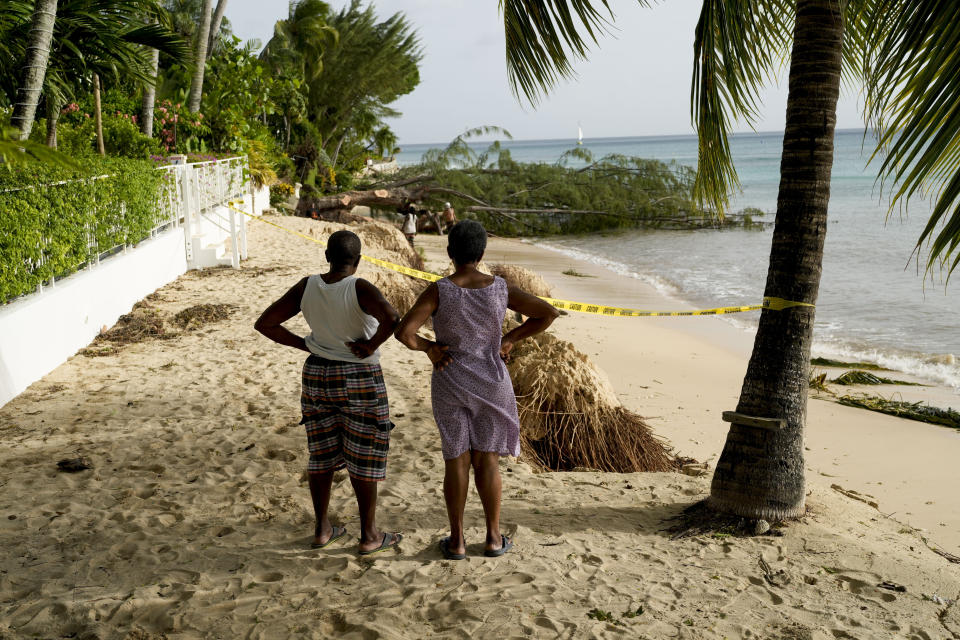 Neighbors look out at beach erosion and a fallen tree the day after Hurricane Beryl hit St. James, Barbados, Tuesday, July 2, 2024. (AP Photo/Ricardo Mazalan)