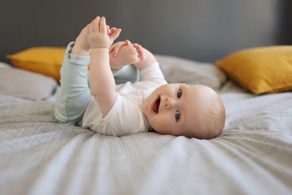 portrait of a smiling baby at home holding their feet