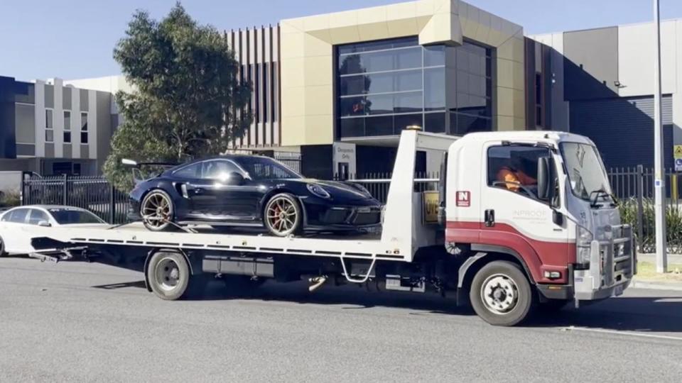 A luxury car on the back of a tow truck.