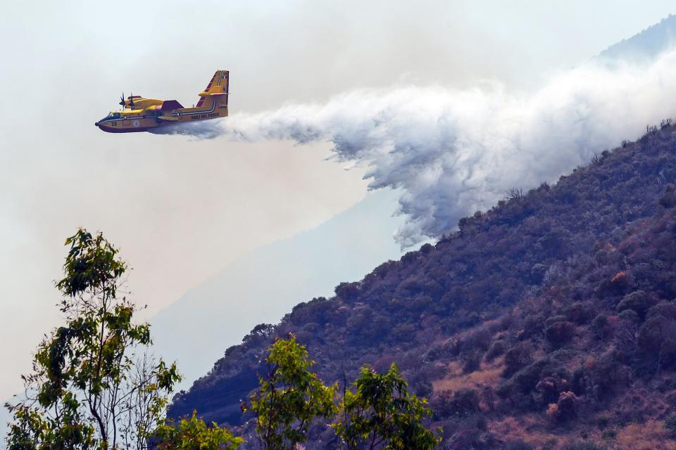 A Canadair water-bombing plane releases water on the Stromboli volcano's hillside on July 4, 2019 a day after it erupted. The planes battled to put out fires started by two massive explosions, which sent plumes of smoke over a mile into the sky.