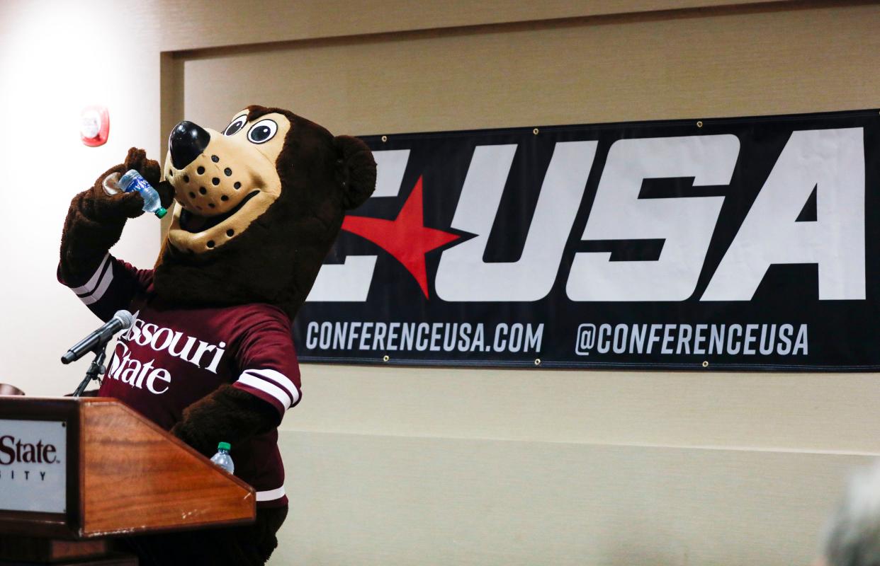 The Missouri State mascot Boomer mimes drinking water in front of a Conference USA banner at Great Southern Bank Arena on Monday, May 13, 2024.