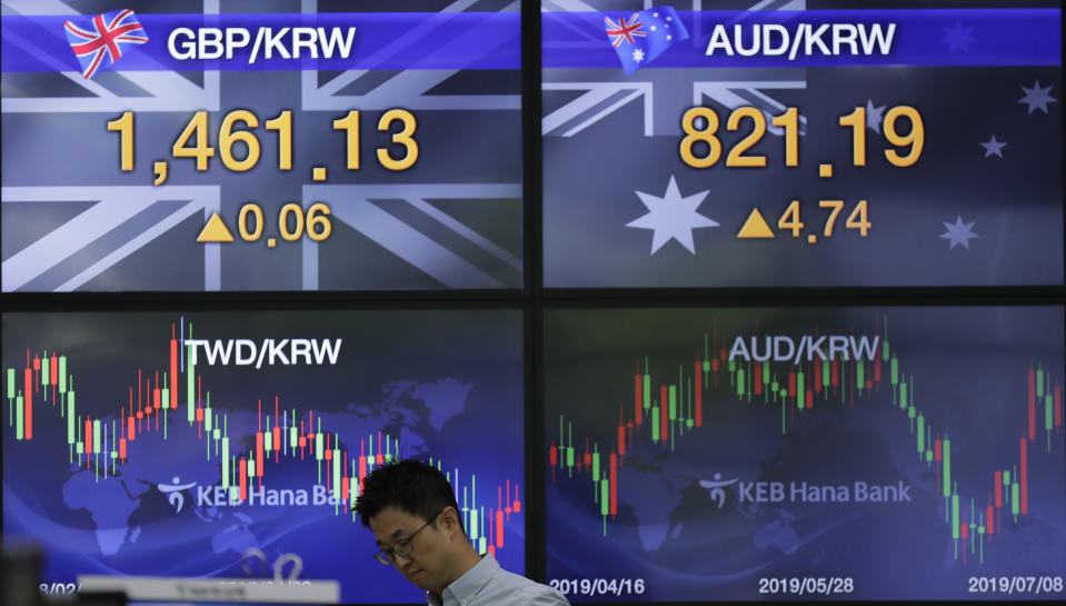 A currency trader walks by the screens showing the foreign exchange rates at the foreign exchange dealing room in Seoul, South Korea, Monday, July 8, 2019. Asian stocks tumbled Monday after relatively strong U.S. employment data tempered hopes the Federal Reserve might cut interest rates. (AP Photo/Lee Jin-man)