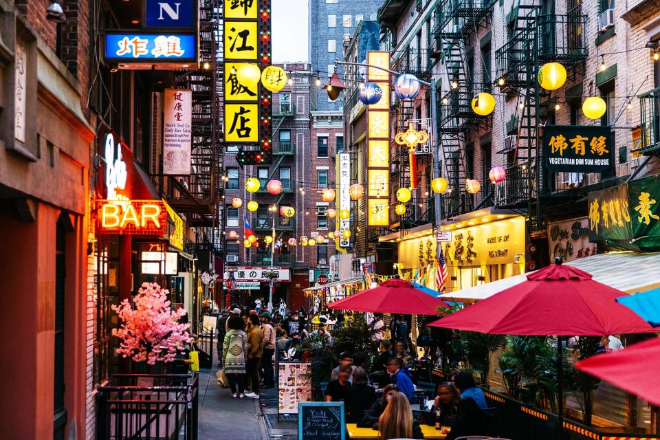 Crowded illuminated street with restaurants in bars in Chinatown, New York City, USA