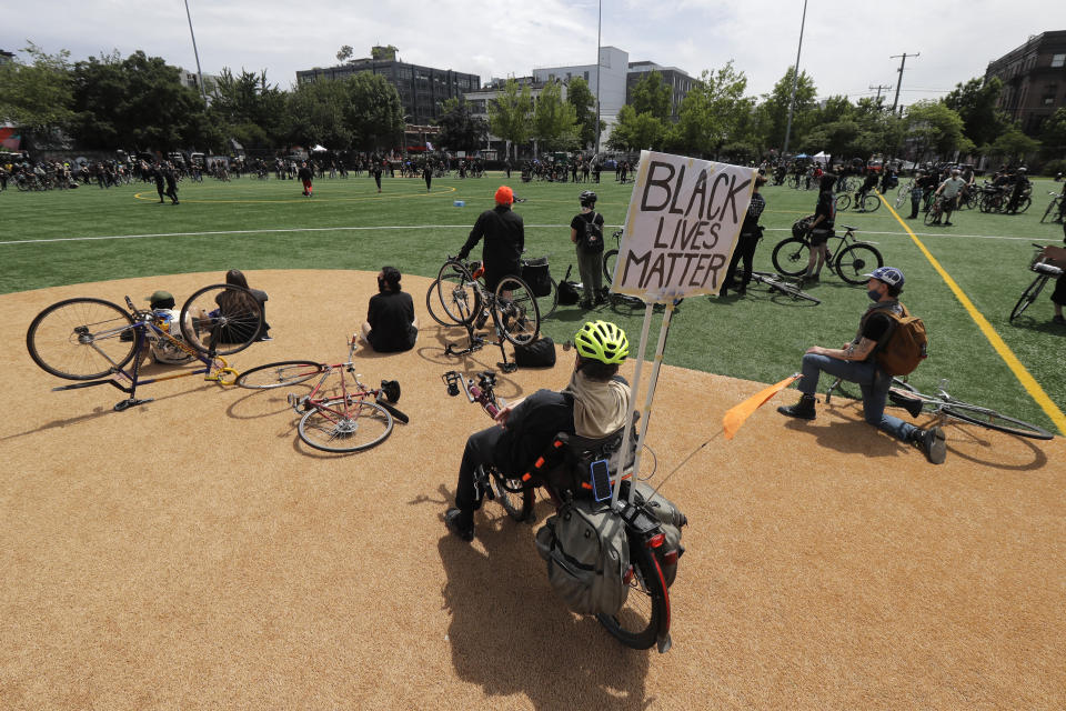 A cyclist displays a sign that reads "Black Lives Matter" during a rally at Cal Anderson Park after a "Ride for Justice," Thursday, June 11, 2020, Seattle. People rode to the park and then took part in a rally to protest against police brutality and racial inequality. (AP Photo/Ted S. Warren)