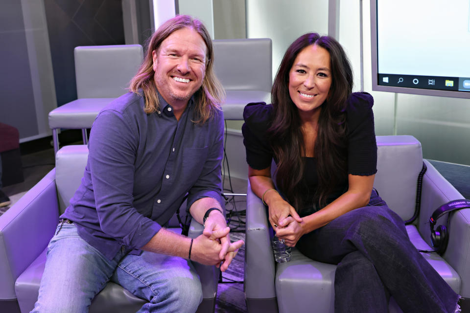 Chip and Joanna pose together while sitting in sofa chairs