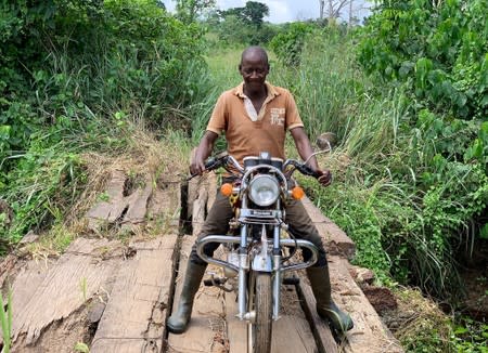 Ivorian cocoa farmer, N'Da Kouakou Kinimo, sits on a motorbike in the village of Edoukoukro