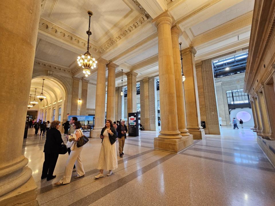 a group of people in a large building with columns and a large pillar