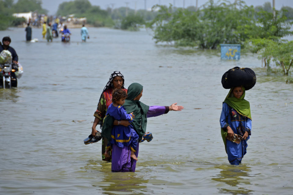 People wade through floodwaters in Sohbatpur, a district of Pakistan's southwestern Baluchistan province, Monday, Aug. 29, 2022. International aid was reaching Pakistan on Monday, as the military and volunteers desperately tried to evacuate many thousands stranded by widespread flooding driven by "monster monsoons" that have claimed more than 1,000 lives this summer. (AP Photo/Zahid Hussain)