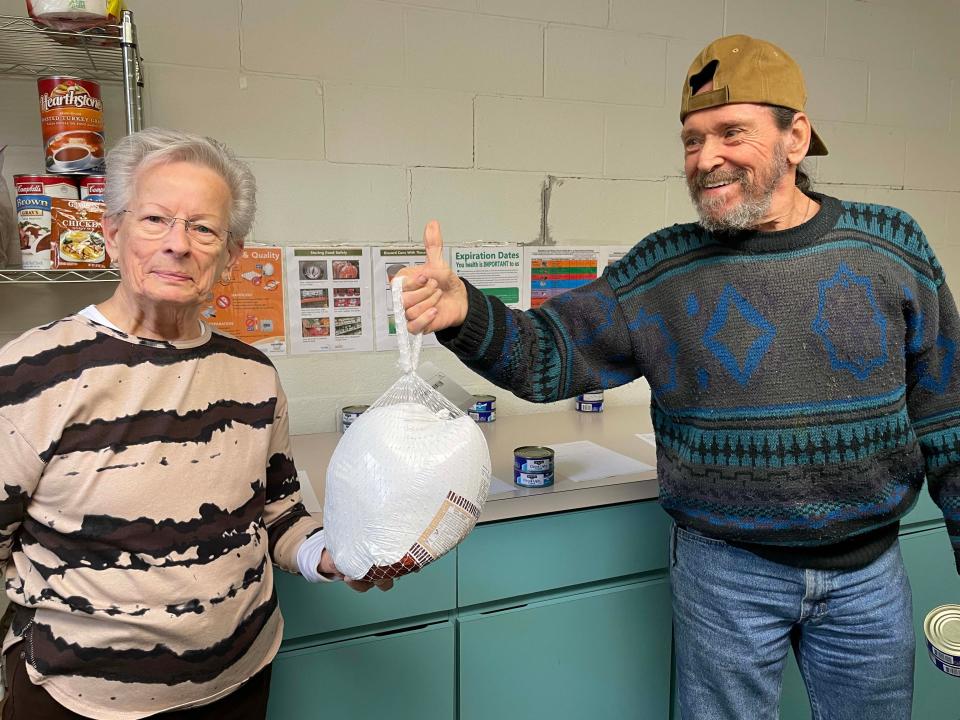 Food pantry coordinator Suzanne Hawley hands off a small turkey to volunteer Harry Collis at Center Faith Church Friday, Jan. 21, 2022.