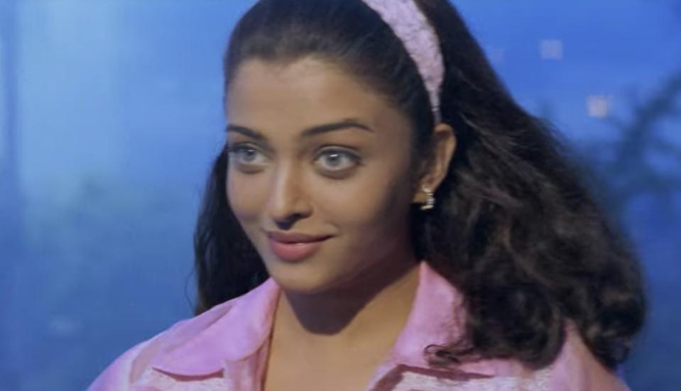 Aishwarya Rai wears a pink top and pink headband. She smiles.