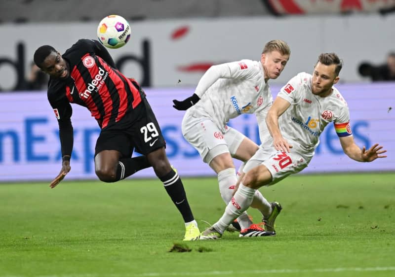 Eintracht Frankfurt's Niels Nkounkou (L) and Mainz's Jonathan Burkhardt (C) and Silvan Widmer battle for the ball during the German Bundesliga soccer match between Eintracht Frankfurt and  1. FSV Mainz 05 at the Deutsche Bank Park. Arne Dedert/dpa