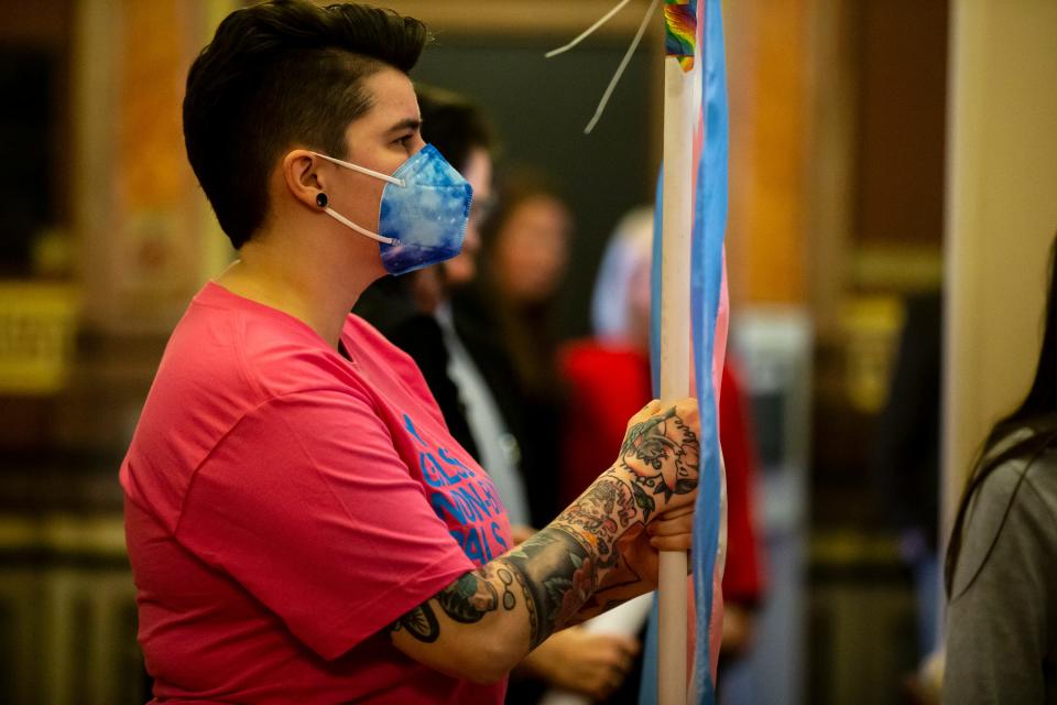 Becky Smith, Executive Director of Iowa Safe Schools, holds a transgender flag behind the signing ceremony for House File 2416, prohibiting transgender women and girls from competing in female sports offered by Iowa schools, colleges and universities, on Thursday, March 3, 2022, in the rotunda of the Iowa State Capitol, in Des Moines. 