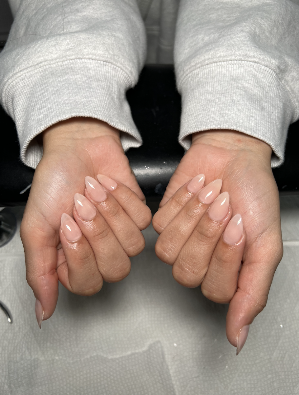 Person displaying hands with long, manicured nails in a neutral shade