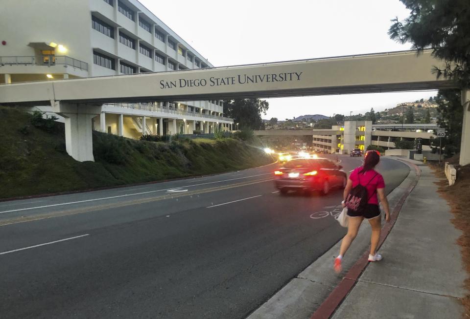 This Sept. 17, 2020 photo shows a busy street cutting through the San Diego State University campus in San Diego, Calif. A coronavirus outbreak of more than 700 cases reported at San Diego State University has put all of San Diego County, with more than 3 million people, at risk of having to close indoor dining and shopping, many for a third time under California guidelines. (AP Photo/Elliot Spagat)