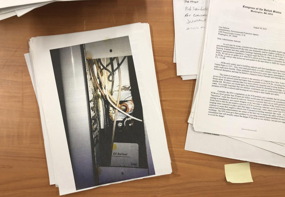 In this Feb. 5, 2019, photo, documents and an image of an old fluorescent light ballast sit on a table at the U.S. Environmental Protection Agency Region 2 headquarters in New York. The agency and a lawsuit from parents prompted the replacement of hundreds of thousands of PCB-containing light ballasts in New York City Public Schools. (AP Photo/Martha Irvine)