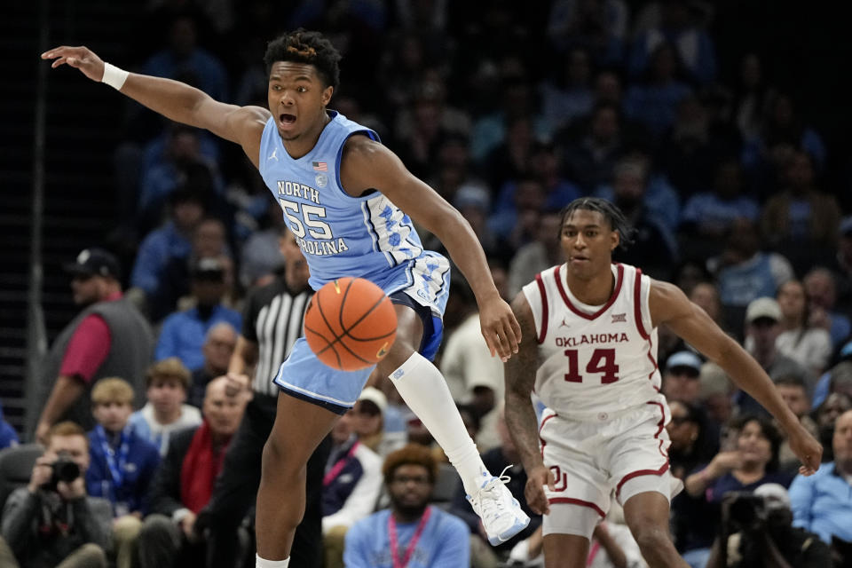 North Carolina forward Harrison Ingram and Oklahoma forward Jalon Moore chase a loose ball during the first half of an NCAA college basketball game Wednesday, Dec. 20, 2023, in Charlotte, N.C. (AP Photo/Chris Carlson)