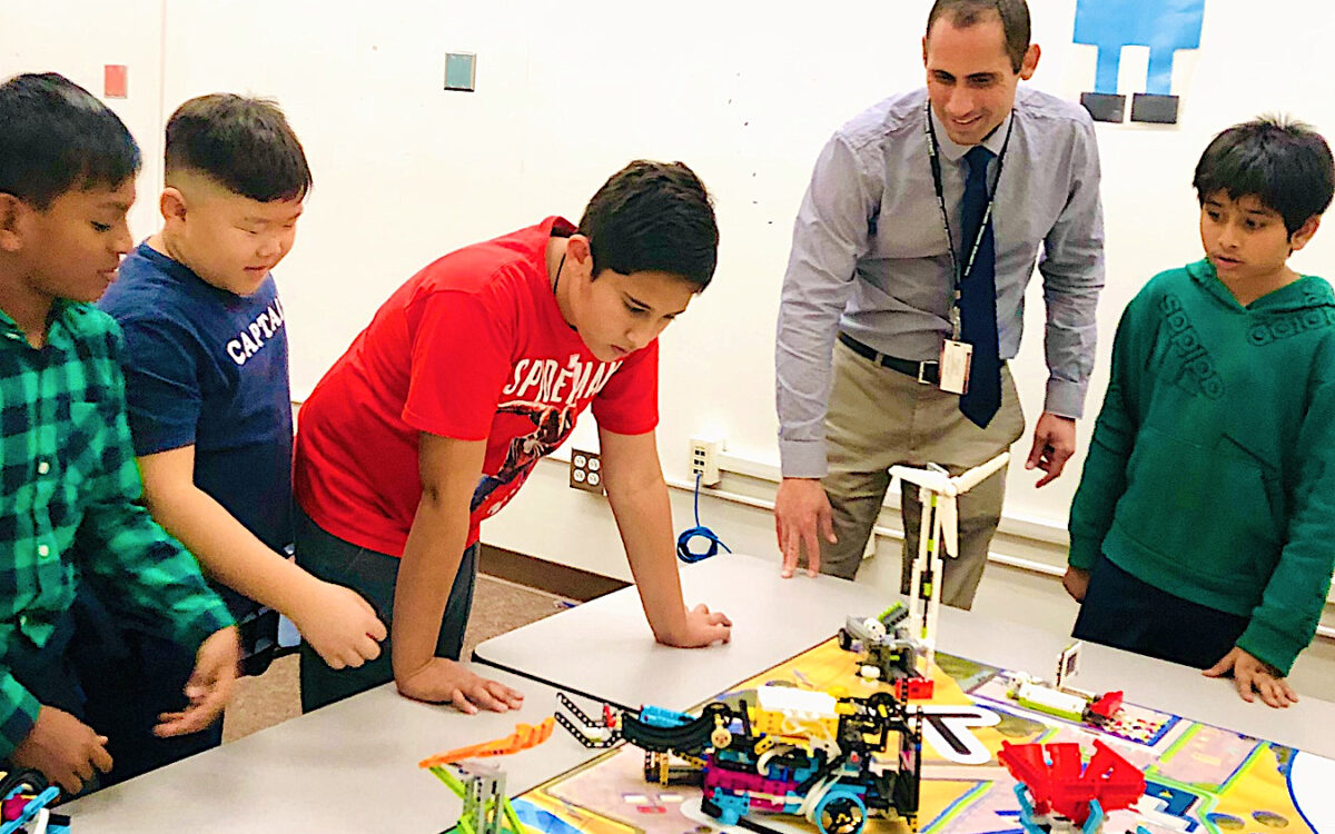 Principal Miguel Marco checks in with members of the Wittmann Elementary School robotics team, who were working on coding for their "Dash and Dot" robot. They turned theirs into a cat that meows when you pet or talk to it.