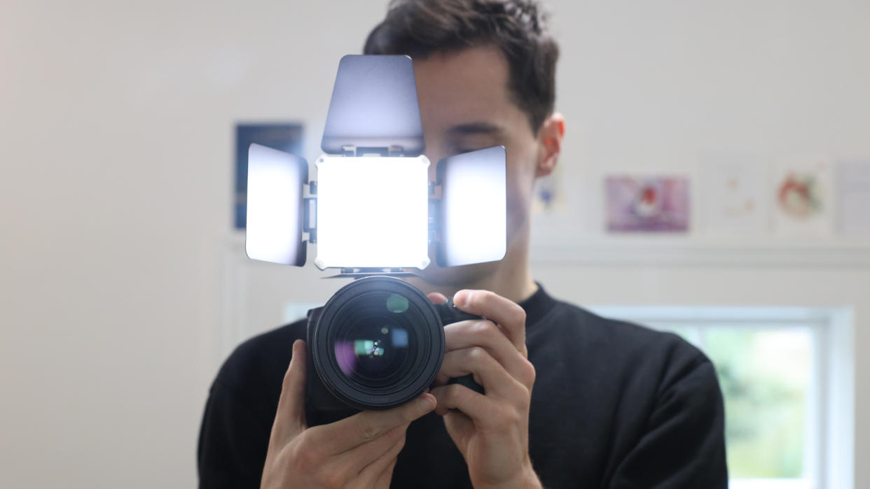  Zhiyun FIVERAY M20C LED panel mounted on a camera and held in front of a man's face. 