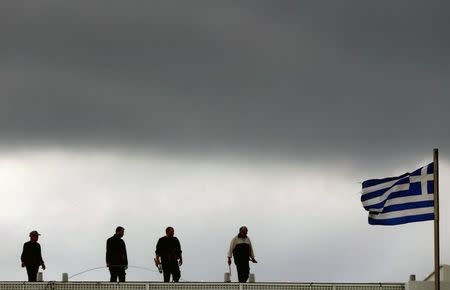 Workers are seen atop a building next to a Greece flag in Syntagma square in Athens March 10, 2015. REUTERS/Yannis Behrakis