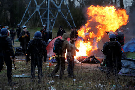 A burning tent is seen, as French riot police push back Iranian Kurdish migrants, during the dismantling of a camp in Calais, France, January 10, 2019. Picture taken January 10, 2019. REUTERS/Pascal Rossignol