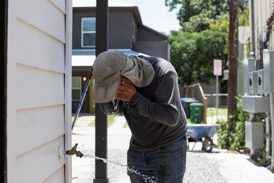 Fernando Oviedo splashes his face with water in between placing gravel at a new build in a residential neighborhood in the middle of the day during a period of hot weather in San Antonio, Texas (REUTERS)