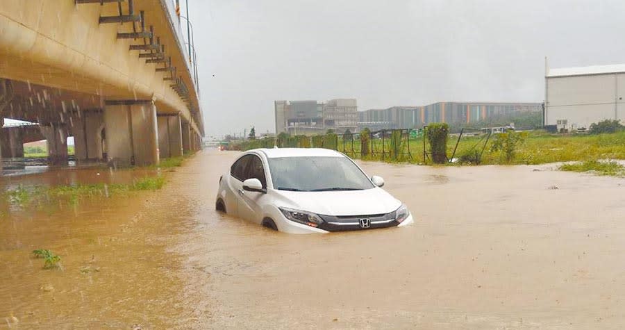 觀音草漯地區有自小客車在水中拋錨，水淹半個輪胎高。（消防局提供）