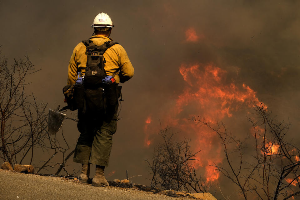 A firefighter watches as a wildfire burns Wednesday, Oct. 13, 2021, in Goleta, Calif. A wildfire raging through Southern California coastal mountains threatened ranches and rural homes and kept a major highway shut down Wednesday as the fire-scarred state faced a new round of dry winds that raise risk of flames. The Alisal Fire covered more than 22 square miles (57 square kilometers) in the Santa Ynez Mountains west of Santa Barbara. (AP Photo/Ringo H.W. Chiu)