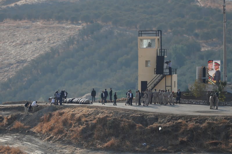 Jordanian soldiers pray as others walk around in an area known as Naharayim in Hebrew and Baquora in Arabic, in the border area between Israel and Jordan, as seen from the Israeli side