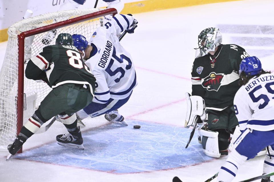 Minnesota's Frederick Gaudreau, left, and Toronto's Mark Giordano, second left, in action behind Minnesota's goalkeeper Marc-Andre Fleury during the NHL Global Series Sweden ice hockey match between Toronto Maple Leafs and Minnesota Wild at Avicii Arena in Stockholm, Sweden, Sunday, Nov. 19, 2023.(Claudio Bresciani/TT via AP)
